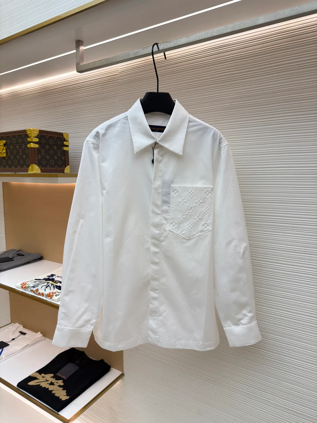 LOUIS VUITTON Embossed Pocket Lapel Shirt ●Original version: Purchased and developed for 3989 ●Item number: 1681491-B05 ●Fabric: Cotton twill woven fabric ●Technology: Concave embossed printing ●Color: white ●Version: Fitted version ●Weight: about 370 grams ●Size: XS-S-M-L ●Description: The twill pattern is obvious on the front of the fabric and blurry on the reverse. Single yarn is used in both warp and weft directions, and the linear density is close. The warp density of the fabric is slightly higher than the weft density, and the hand feel is relatively soft. The fabric has excellent stability, is not easy to deform, and prevents bulging; cotton fiber has good hygroscopicity, which keeps the fabric in a water balance, making people feel comfortable, and adding to the sophistication of the fabric. The concave and convex embossing process is formed by heating and shaping the upper and lower dies. The rollers press the fabric at a certain temperature, and the three-dimensional hierarchical convex surface is produced through mechanical embossing. The fabric produces a concave and convex pattern with a relief-style three-dimensional effect and a special gloss effect. The three-dimensional shape, pattern and text have a strong three-dimensional sense, adding a decorative art effect, clear layers, concentrated three-dimensional image, and accurate perspective angle. The collar can be adjusted with buttons for both formality and comfort; the pleats and tabs at the back are classic shirting techniques, with the pleats providing extra room for movement and the tabs keeping the shirt in shape when hanging. The button front uses custom-fit buttons that are positioned accordingly, and together these details ensure the shirt's functionality and crisp look. The overall wiring is straight and delicate, the fabric is comfortable and soft, and the color is consistent without color difference. It can be matched with the same style to create a fashionable look and control various occasions. Customized accessories, complete with three standards, same style for men and women!